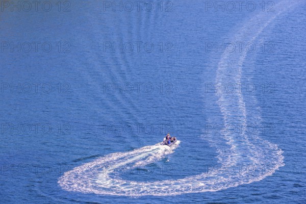 Inflatable boat with people turning on the sea and making wake pattern on the water surface, Crozon peninsula, Bretagne, France, Europe