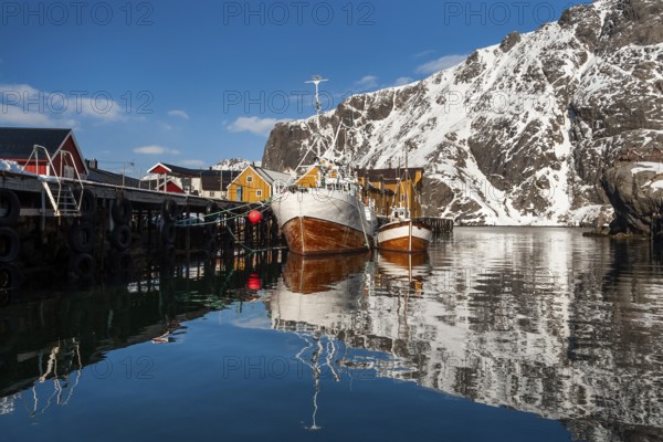 Fishing boats, fishing village with yellow houses in front of snowy mountains, Nusfjord, Flakstadoya or Flakstadøy, Vestvågøya island, Lofoten, Norway, Europe