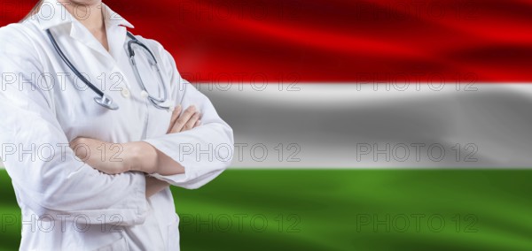 Doctor With Crossed Arms On Hungarian Flag. Hungary Health And Care Concept. Female Doctor On Hungarian Flag