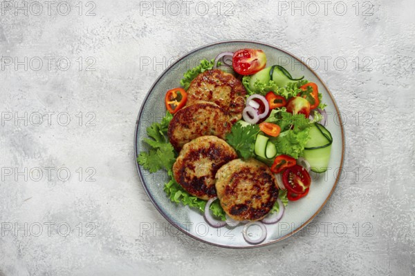 Fried chicken cutlets, minced chicken, with vegetables, on gray, with vegetable salad, top view, homemade, no people