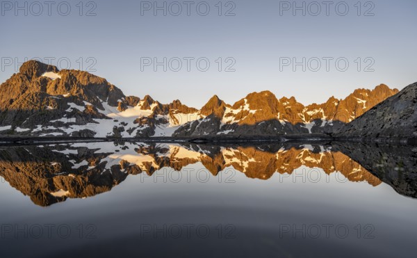 Rocky mountain peaks reflected in a small pond, mountain landscape with alpenglow at sunrise, at the Trollfjord Hytta, at the Trollfjord, Lofoten and Vesterålen, Nordland, Norway, Europe