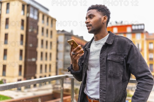 African man holding mobile sending a voice message with city views in the background