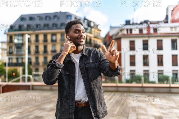 Cool african man dancing listening to music with earbuds in the city