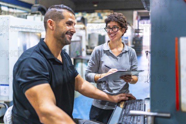 Manager and worker talking while working using computer in a cnc metal factory