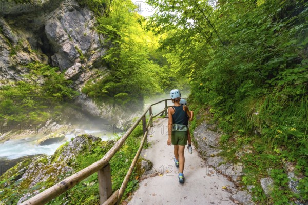 Tourists walking on a pathway along the radovna river in vintgar gorge, enjoying the scenic beauty of the canyon near bled, slovenia