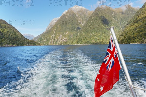 New Zealand flag waving, Milford Sound, South Island, Southland, New Zealand, Australasia, Oceania