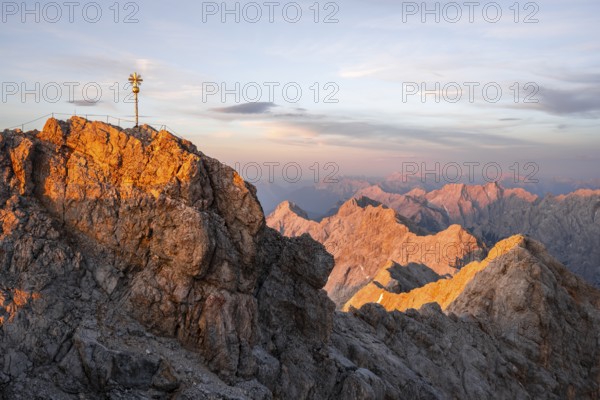 Summit of the Zugspitze with golden summit cross, alpenglow at sunset, Northern Limestone Alps, Wetterstein Mountains, Bavaria, Germany, Europe