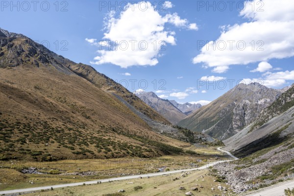 Gravel track in a valley, picturesque mountain landscape with white mountain peaks, Tian Shan Mountains, Issyk-Kul, Kyrgyzstan, Asia