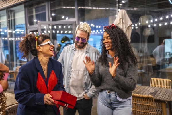 Happy woman receiving birthday gift during night party with friends in a bar