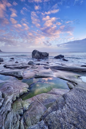 Rocks on beach of fjord of Norwegian sea in winteron sunset. Utakliev beach, Lofoten islands, Norway, Europe