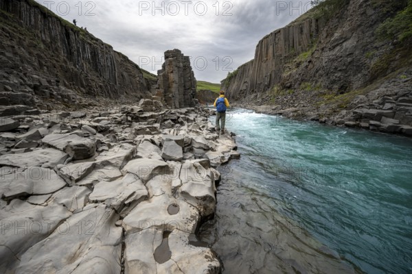 Tourist standing by the river in Stuðlagil Canyon, turquoise blue river between basalt columns, Egilsstadir, Iceland, Europe