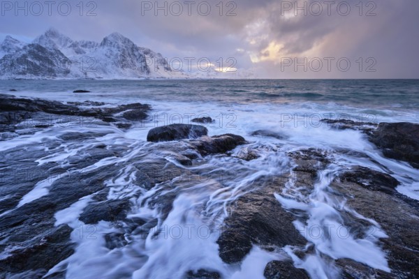 Beach of Norwegian sea on rocky coast in fjord on sunset in winter. Vareid beach, Lofoten islands, Norway, Europe