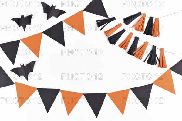 Halloween background with garlands and paper bats in traditional colors orange and black on white background with copy space