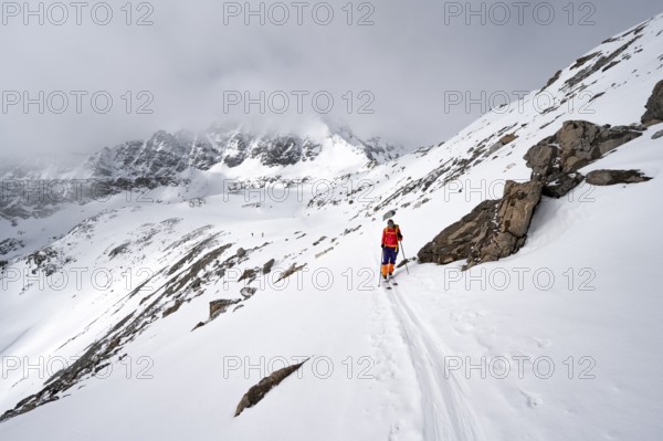Ski tourer in wintry mountain landscape with cloudy mountain peaks, ascent to Piz Laviner, Grisons Haute Route, Albula Alps, Rhaetian Alps, Grisons, Eastern Switzerland, Switzerland, Europe