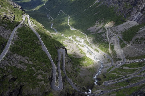 A winding road meanders through a green valley between steep mountains, Trollstigen, Andalsnes, Norway, Europe