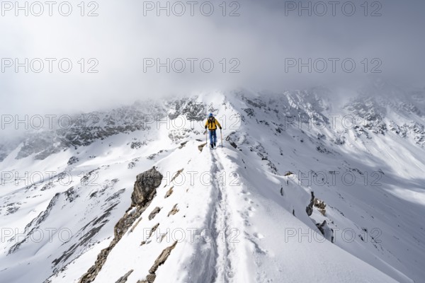 Mountaineer climbing up the narrow ridge of Piz Laviner, view of wintry mountain landscape, Grisons Haute Route, Albula Alps, Rhaetian Alps, Grisons, Eastern Switzerland, Switzerland, Europe