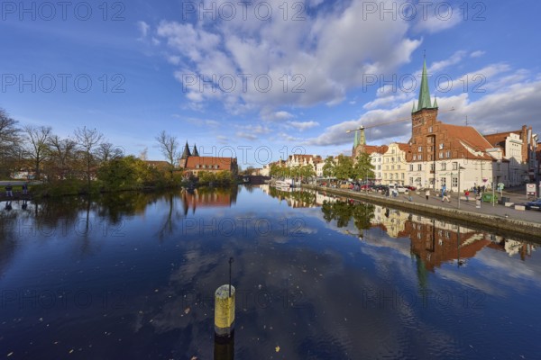 River Trave, quay wall, historic buildings, church towers of St. Marien and St. Petri, reflections on the water surface, blue sky with cumulus clouds, street An der Obertrave, Hanseatic City of Lübeck, Schleswig-Holstein, Germany, Europe