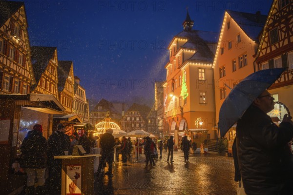 People with umbrellas strolling through the Christmas-lit old town market at night, Christmas market Calw, Black Forest, Germany, Europe