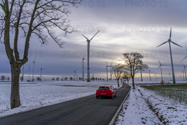 Country road, wind farm, north of Lichtenau, self-proclaimed energy town, over 190 wind turbines and over 1200 solar panels generate 10 times as much electricity as the community of 11, 900 inhabitants consumes, largest onshore cluster of wind turbines in Germany, winter, slightly snowy landscape, North Rhine-Westphalia, Germany, Europe