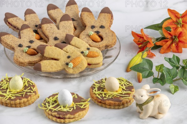 Bunny biscuits with carrots and egg decoration next to orange flowers and Easter bunny