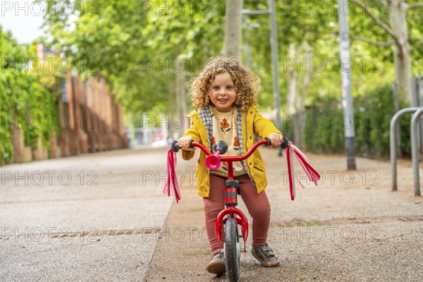 Full length of a smiling caucasian cute happy girl riding a pink bicycle in the park