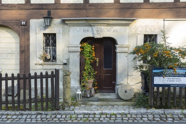 Historic door frame and loving decoration with millstone and flowers in front of a typical half-timbered house in Waltersdorf, Großschönau, Saxony, Germany, Europe