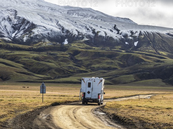 Pickup camper on gravel road, early snow on mountain range, along road Landmannaleid F225, Fjallabak Nature Reserve, Iceland, Europe