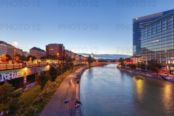 Riverbank at sunset with modern buildings and colourful lighting, Vienna