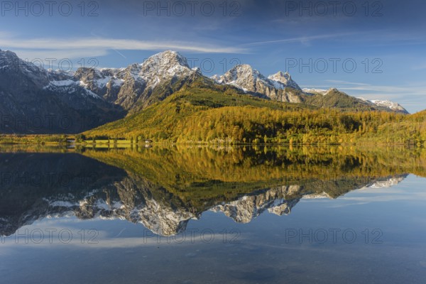 Lake Almsee in autumn with mountains reflected in the lake. Blue sky