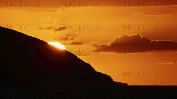 Soft orange light of the sun behind a mountain, cloud formations in the sky, sunset, Kassos, Karpathos, offshore islands, Dodecanese, Greek Islands, Greece, Europe