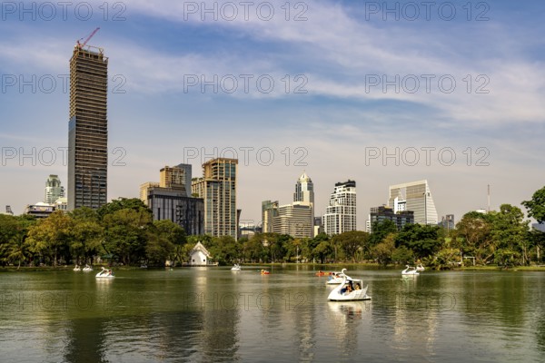 Swan pedal boat on Lumphini Lake in Lumphini Park and the skyline of Bangkok, Thailand, Asia
