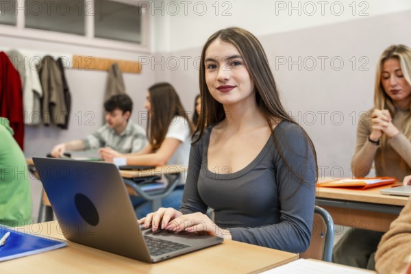 Young woman using laptop in university classroom, participating in an engaging lesson with her classmates