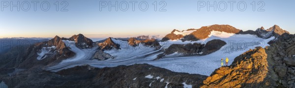 Panorama, atmospheric sunrise in a picturesque mountain landscape, alpenglow, aerial view, mountaineer on the summit of Becher and Übeltalferner glacier, Stubai Alps, South Tyrol, Italy, Europe