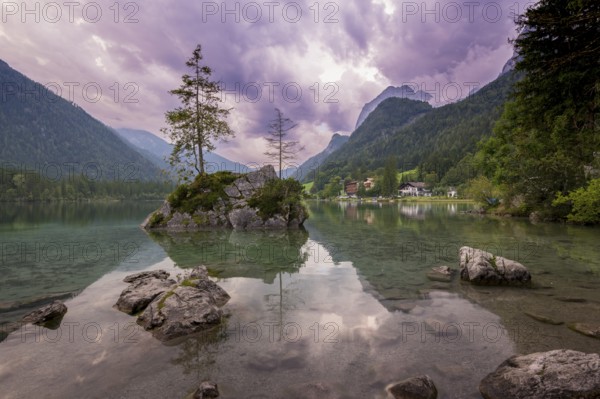 Hintersee with rocks and trees in the foreground, surrounded by mountains after sunset with dramatic cloudy sky, Ramsau, Berchtesgaden National Park, Berchtesgadener Land, Upper Bavaria, Bavaria, Germany, Europe