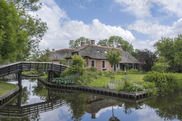 Large house with water reflection and wooden bridge in a peaceful, natural setting, Giethoorn, municipality of Steenwijkerland, province of Overijssel, Netherlands