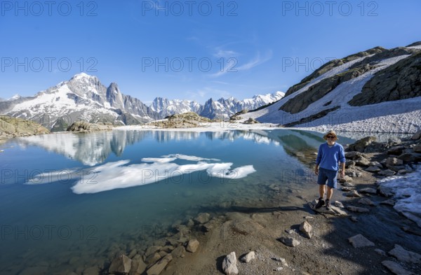 Mountaineer in front of mountain landscape with mountain lake, tourist at Lac Blanc with water reflection, mountain peak Aiguille Verte, Grandes Jorasses, Aiguille du Moine and Mont Blanc, Mont Blanc massif, Chamonix-Mont-Blanc, Haute-Savoie, France, Europe