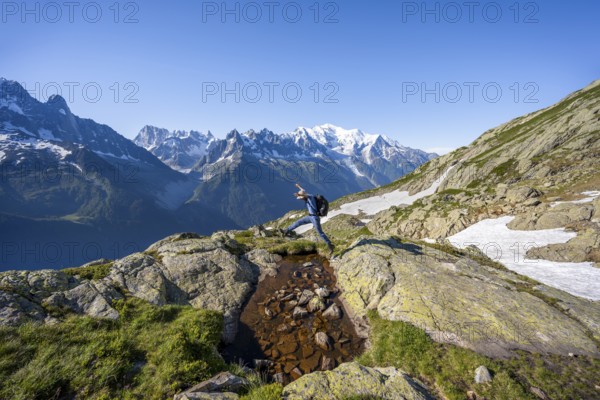 Mountaineer jumping, mountain panorama, view of mountain peaks Grandes Jorasses and Mont Blanc, Mont Blanc massif, Aiguilles Rouges, Chamonix-Mont-Blanc, Haute-Savoie, France, Europe