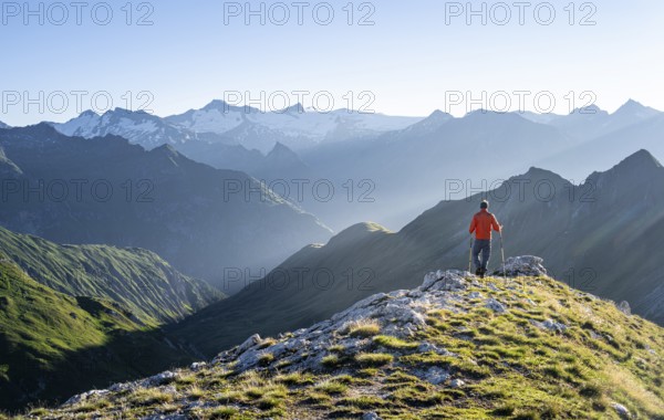 Hiker enjoying the mountain panorama in the morning, Venediger group, behind Dreiherrenkopf, Simonysitze and Großer Geiger, Hohen Tauern, Austria, Europe