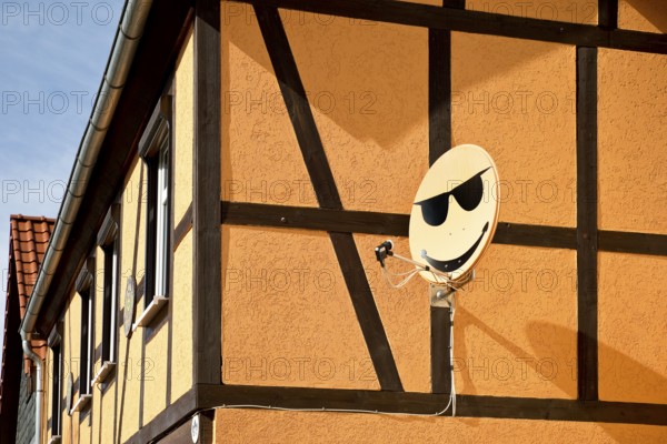 Satellite dish with smiley on a house wall in Langenstein, Halberstadt, Saxony-Anhalt, Germany, Europe