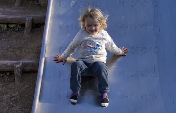Little girl, 3 years, blonde, jumper, Disney, Elsa, ice queen, slides on slide, playground, Stuttgart, Baden-Württemberg, Germany, Europe