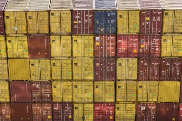 High angle view of stacked yellow and reddish brown MSC, TEX and CAI metal box shipping containers on dock in La Spezia cargo Port, Italy, Europe