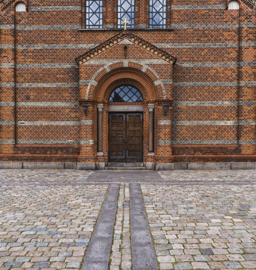 Brick entrance to a church with cross and paved forecourt, Jutland, Denmark, Europe