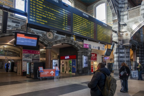 Travelers, commuters looking at timetables in departure hall of the Gent-Sint-Pieters, St Peter's railway station in Ghent, East Flanders, Belgium, Europe