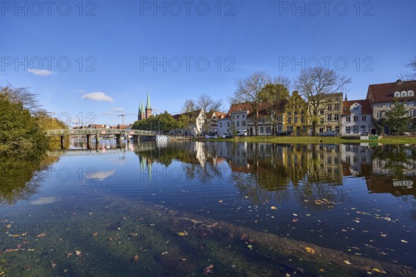 Riverbank of the Trave at high water, pedestrian bridge Dankwartsbrücke, historic houses, trees, reflections on the water surface, blue sky with cumulus clouds, Hanseatic city of Lübeck, independent city, Schleswig-Holstein, Germany, Europe