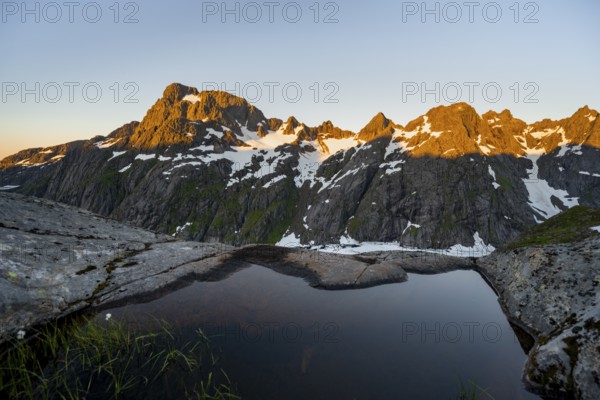 Rocky mountain peaks, small pond in moorland at Trollfjord Hytta, mountain landscape with alpenglow at sunrise, at Trollfjord, Lofoten and Vesterålen, Nordland, Norway, Europe