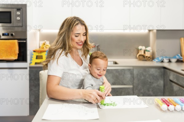 Smiling mother and son enjoying a fun painting session with dot markers, sitting together at the kitchen table, fostering creativity and bonding