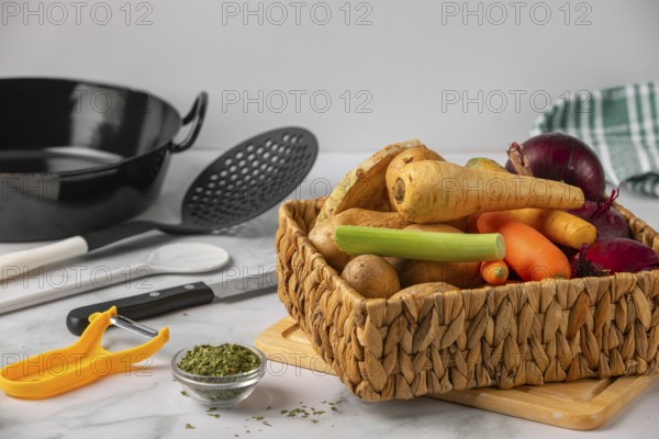 A basket full of different vegetables with kitchen utensils in preparation for cooking