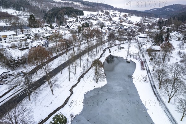 Lake in the spa gardens and the snow-covered district of Elkeringhausen seen from the air, Winterberg, Sauerland, North Rhine-Westphalia, Germany, Europe