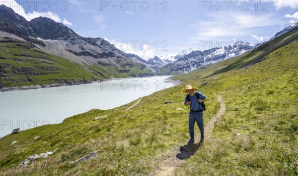 Mountaineer on a hiking trail at a blue mountain lake, Lac des Dix reservoir, Valais Alps, Valais, Switzerland, Europe