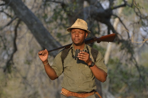 Guide with binoculars and rifle on a walking safari, Mana Pools National Park, Mashonaland West Province, Zimbabwe, Africa